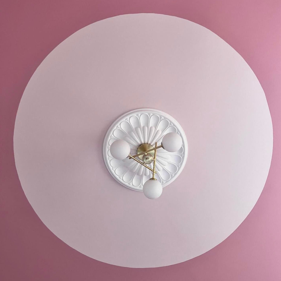 a photo of floral plaster ceiling rose with pink highlights and contemporary lighting fixture.