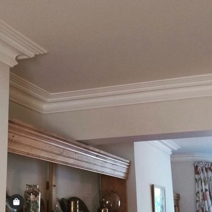 complex section of swan neck plaster coving shown above wooden cabinet