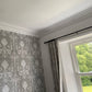 corner joint of plaster cornice shown on floral grey wallpaper