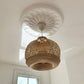 art deco floral plaster ceiling rose shown with basket chandelier in bright room 