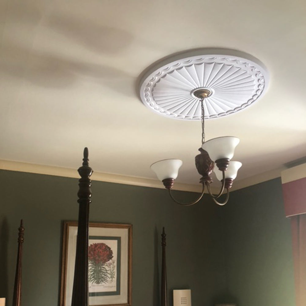 image shows fitted adams sunburst plaster ceiling rose in a green bedroom